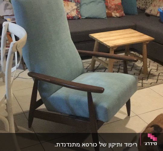 כורסה מרופדת בבד כחול בהיר עם מסגרת עץ כהה